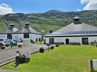 Brennereigebäude in Lochranza vor grünen Hügeln auf der Isle of Arran.