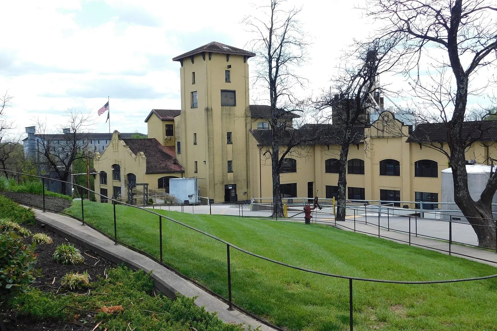 Helle Four-Roses-Gebäude mit Turm und grünem Vorplatz.