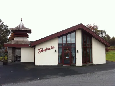 Besucherzentrum von Glenfarclas mit rotem Eingangsrahmen und Brennereischriftzug.