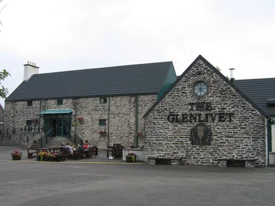 Steinernes Glenlivet-Gebäude mit Uhr im Giebel und großem Brennereischriftzug.