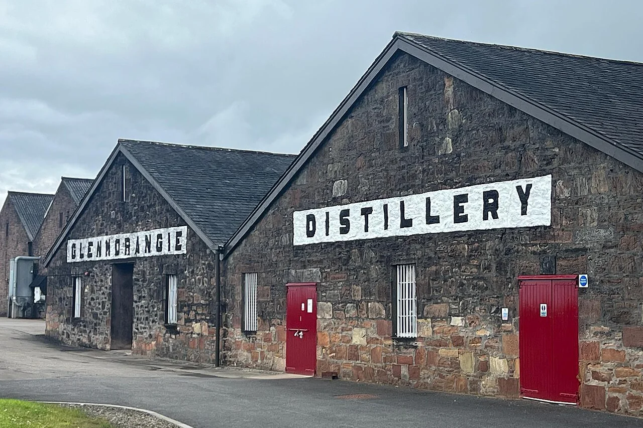 Steinerne Glenmorangie-Lagergebäude mit Brennereischriftzügen und roten Türen.