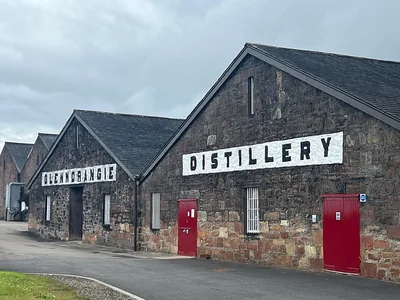Steinerne Glenmorangie-Lagergebäude mit Brennereischriftzügen und roten Türen.