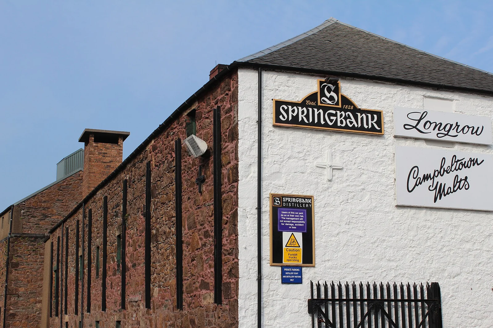 Backsteingebäude der Springbank-Brennerei mit weißer Stirnwand und Brennereischriftzügen.