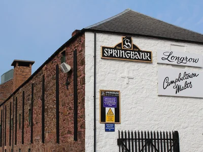 Backsteingebäude der Springbank-Brennerei mit weißer Stirnwand und Brennereischriftzügen.