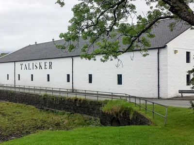 Weiße Talisker-Gebäude mit Schriftzug hinter einer grünen Böschung.
